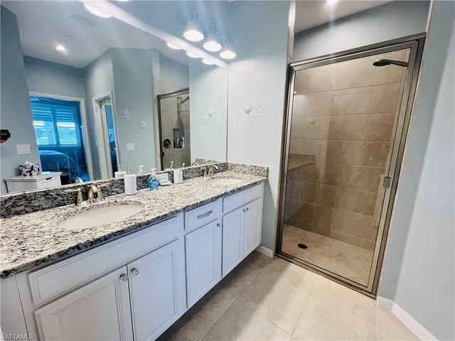 a bathroom with a granite countertop sink a mirror and a shower