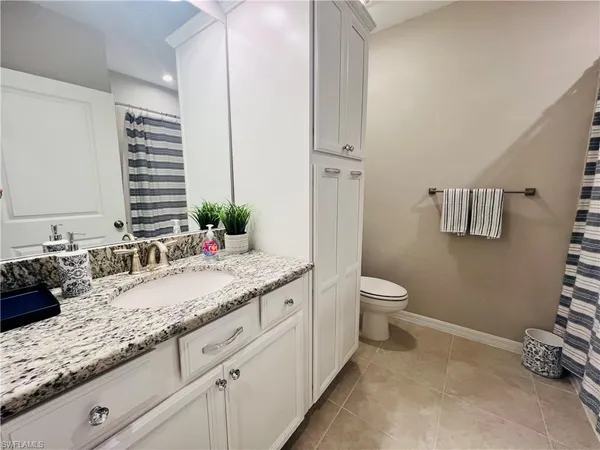 a bathroom with a granite countertop sink a toilet and a mirror