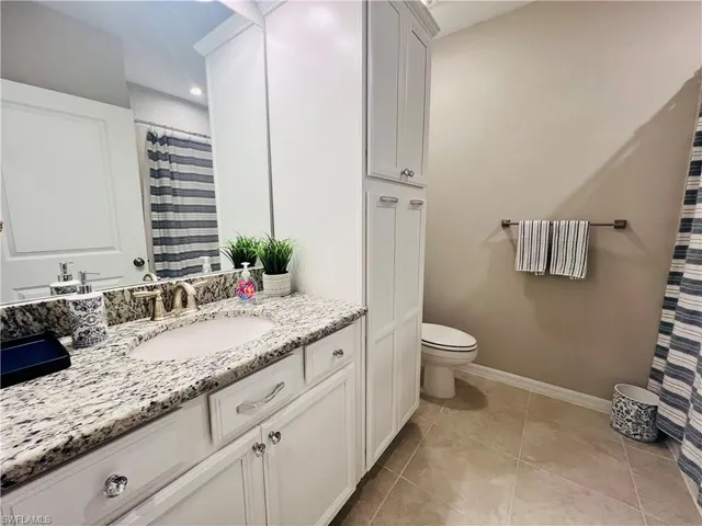 a bathroom with a granite countertop sink a toilet and a mirror