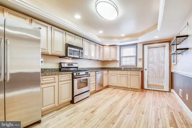 a kitchen with stainless steel appliances granite countertop a stove top oven a sink dishwasher and a refrigerator with wooden floor