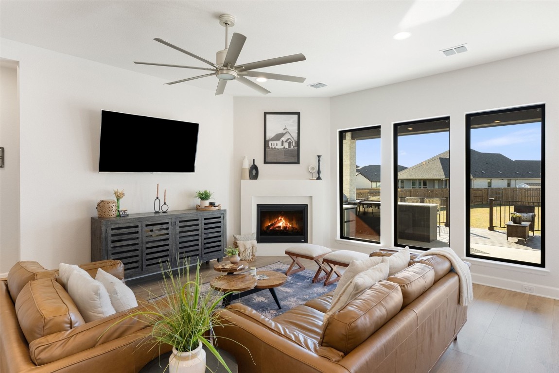 321 Allegheny Way Kyle, TX 78640 - Photo 12 of 40 Living area with a warm lit fireplace, wood finished floors, and a ceiling fan