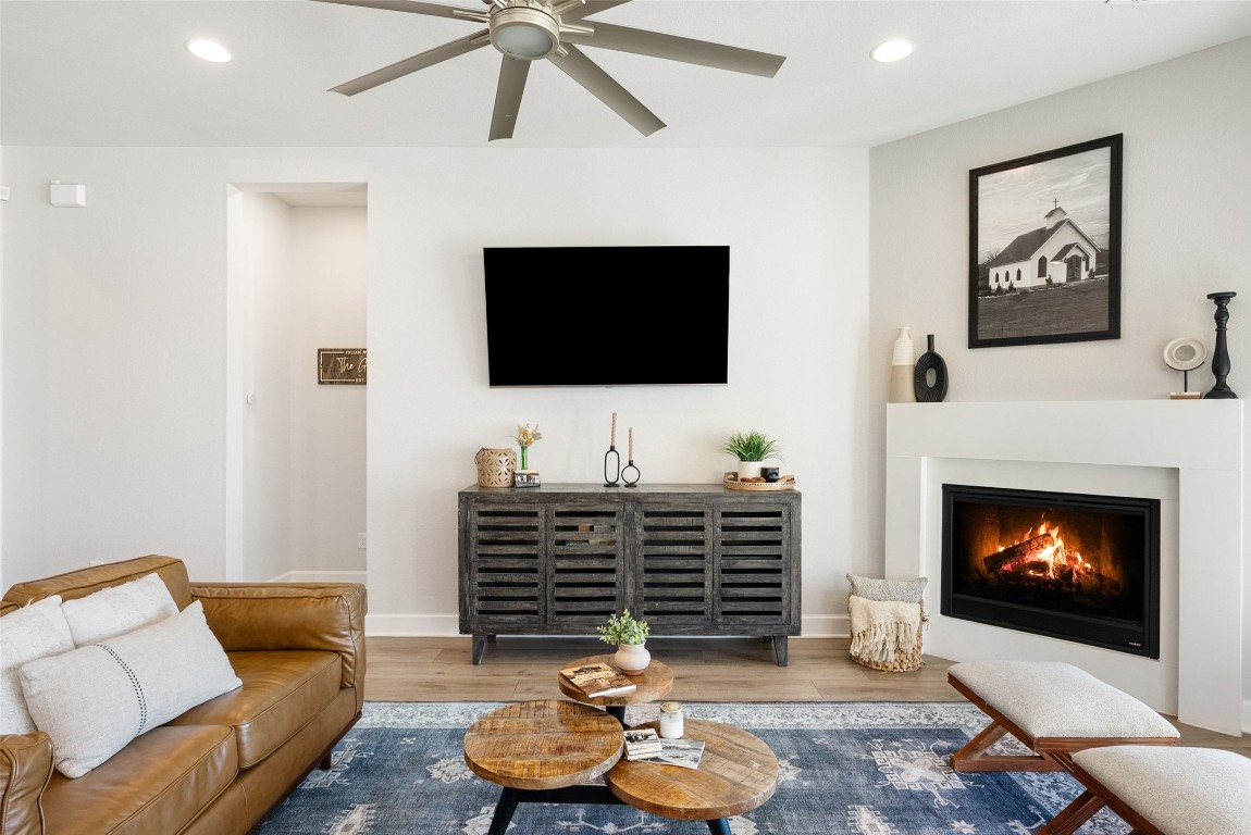 321 Allegheny Way Kyle, TX 78640 - Photo 13 of 40 Living room featuring recessed lighting, a glass covered fireplace, wood finished floors, and a ceiling fan