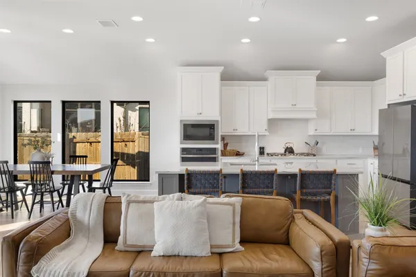 a living room with stainless steel appliances furniture and a kitchen view