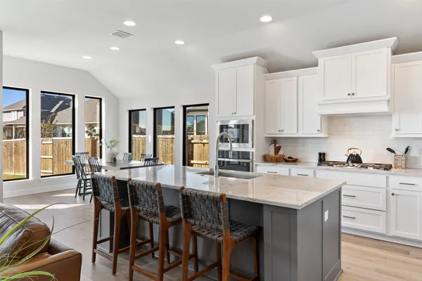 a kitchen with stainless steel appliances a table chairs sink and cabinets