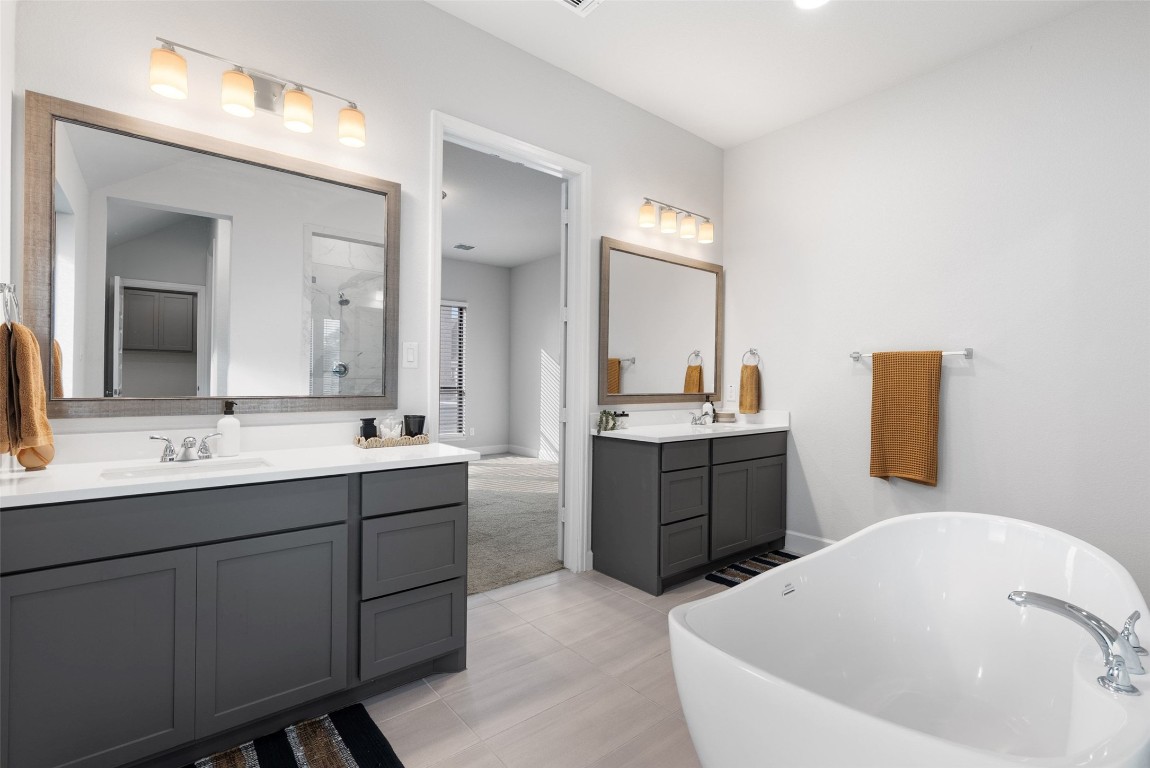 321 Allegheny Way Kyle, TX 78640 - Photo 9 of 40 Bathroom featuring two vanities, a soaking tub, a stall shower, and light tile patterned floors