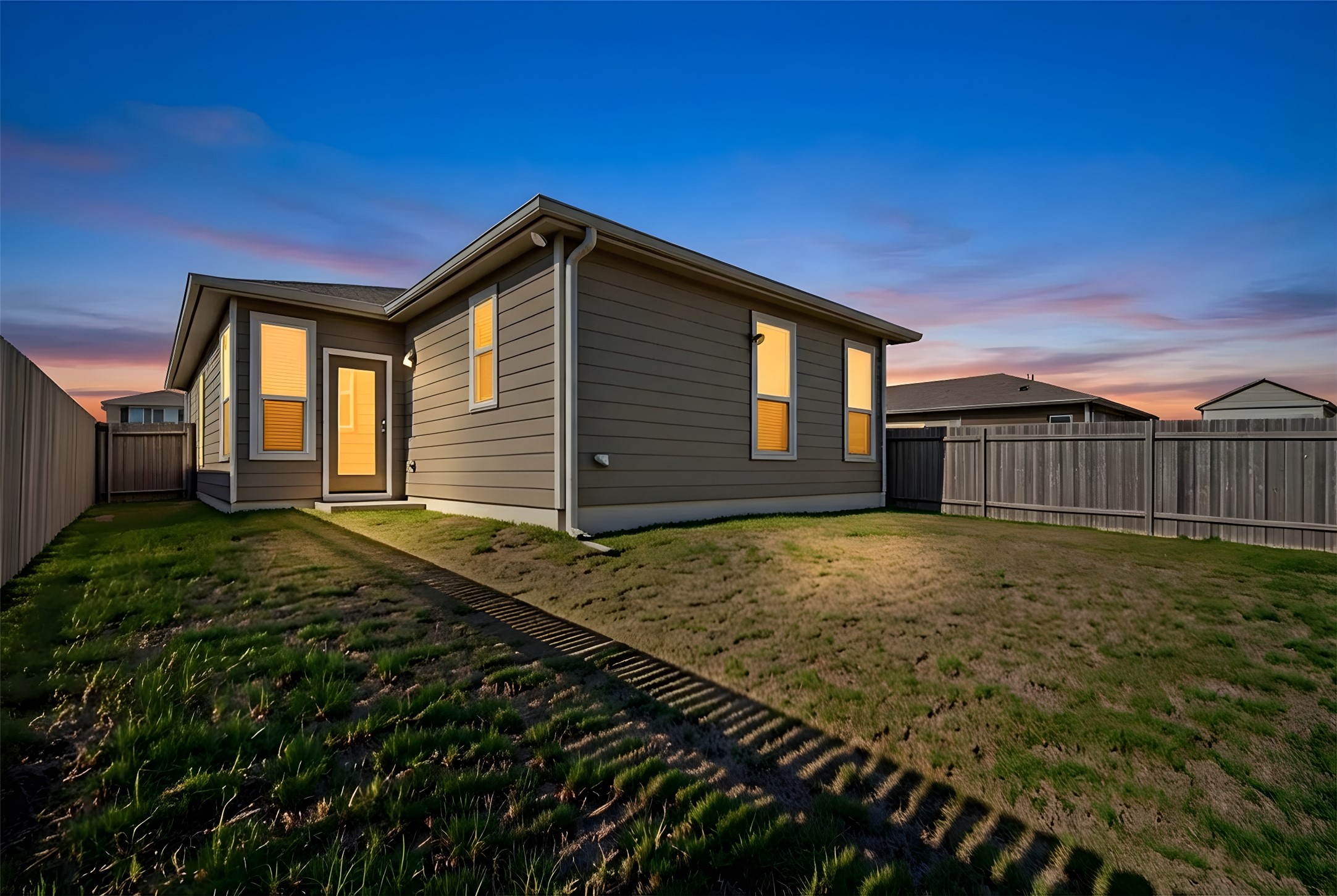 13917 Inaugural Street Manor, TX 78653 - Photo 16 of 39 Back of house at dusk featuring a fenced backyard