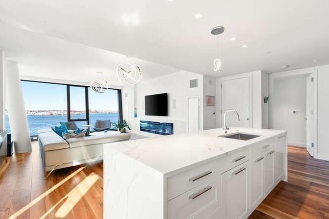 a large white kitchen with a large window and stainless steel appliances