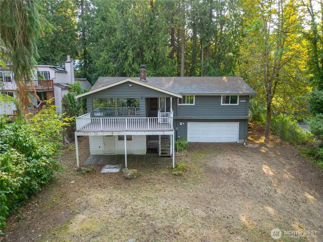 a small barn in front of a house with a small yard and wooden fence