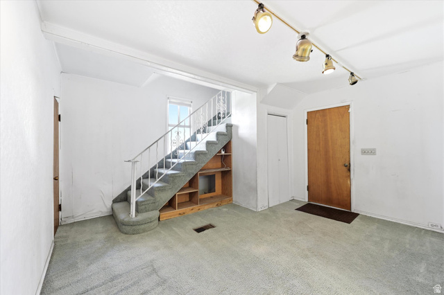 292 West 400 South Springville, UT 84663 - Photo 15 of 37 Carpeted living area featuring a wooden entry door, track lighting, and a staircase with built-in shelving