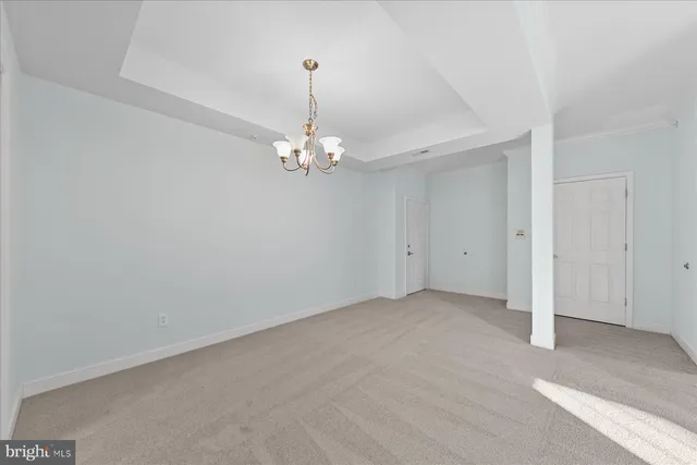 a view of an empty room with a chandelier fan