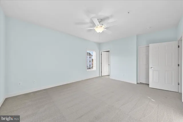 an empty room with a window and ceiling fan
