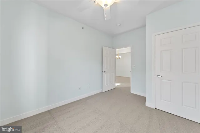 a view of an empty room and chandelier fan
