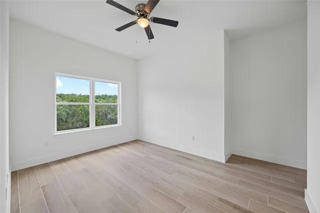 an empty room with wooden floor fan and windows