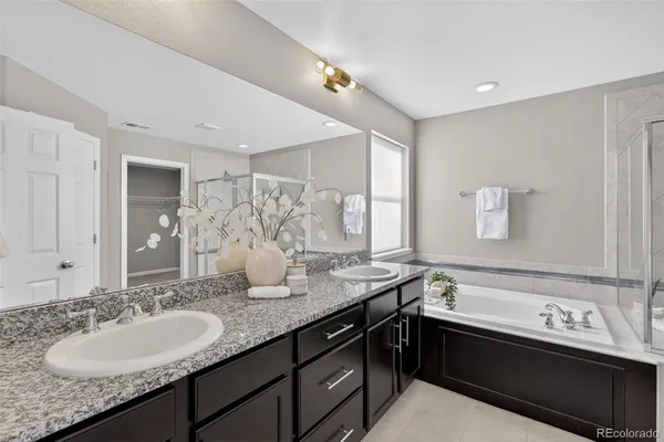 a bathroom with a granite countertop double vanity sink and mirror