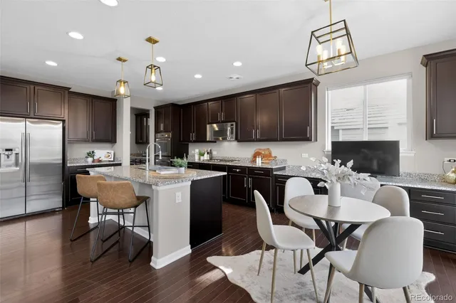 a kitchen with a dining table chairs refrigerator and microwave