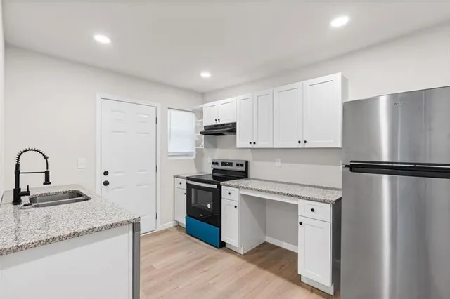 a kitchen with granite countertop white cabinets and stainless steel appliances
