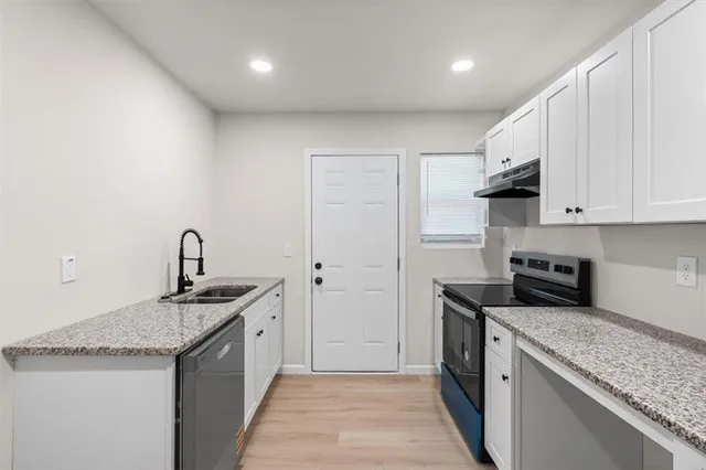 a kitchen that has a sink a stove and a oven