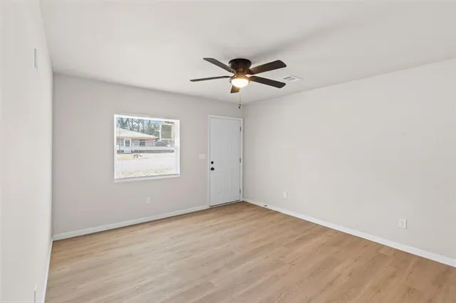 an empty room with a window and ceiling fan