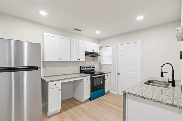 a kitchen with stainless steel appliances granite countertop a refrigerator sink and stove