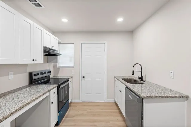 a kitchen with granite countertop sink stainless steel appliances and white cabinets