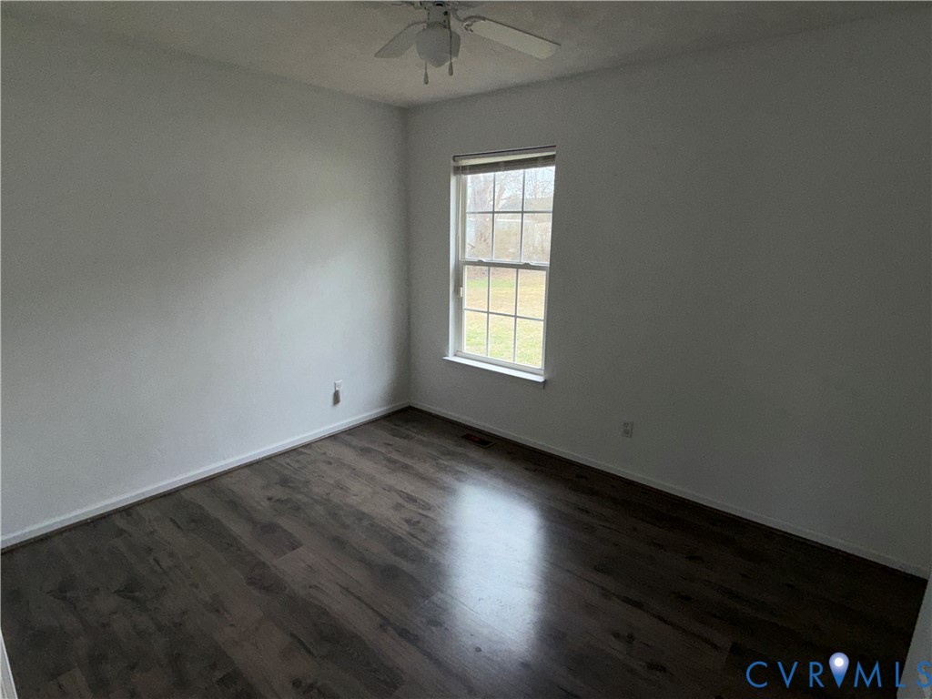 117 Pleasant Spring Avenue Waverly, VA 23890 - Photo 5 of 12 an empty room with wooden floor and windows