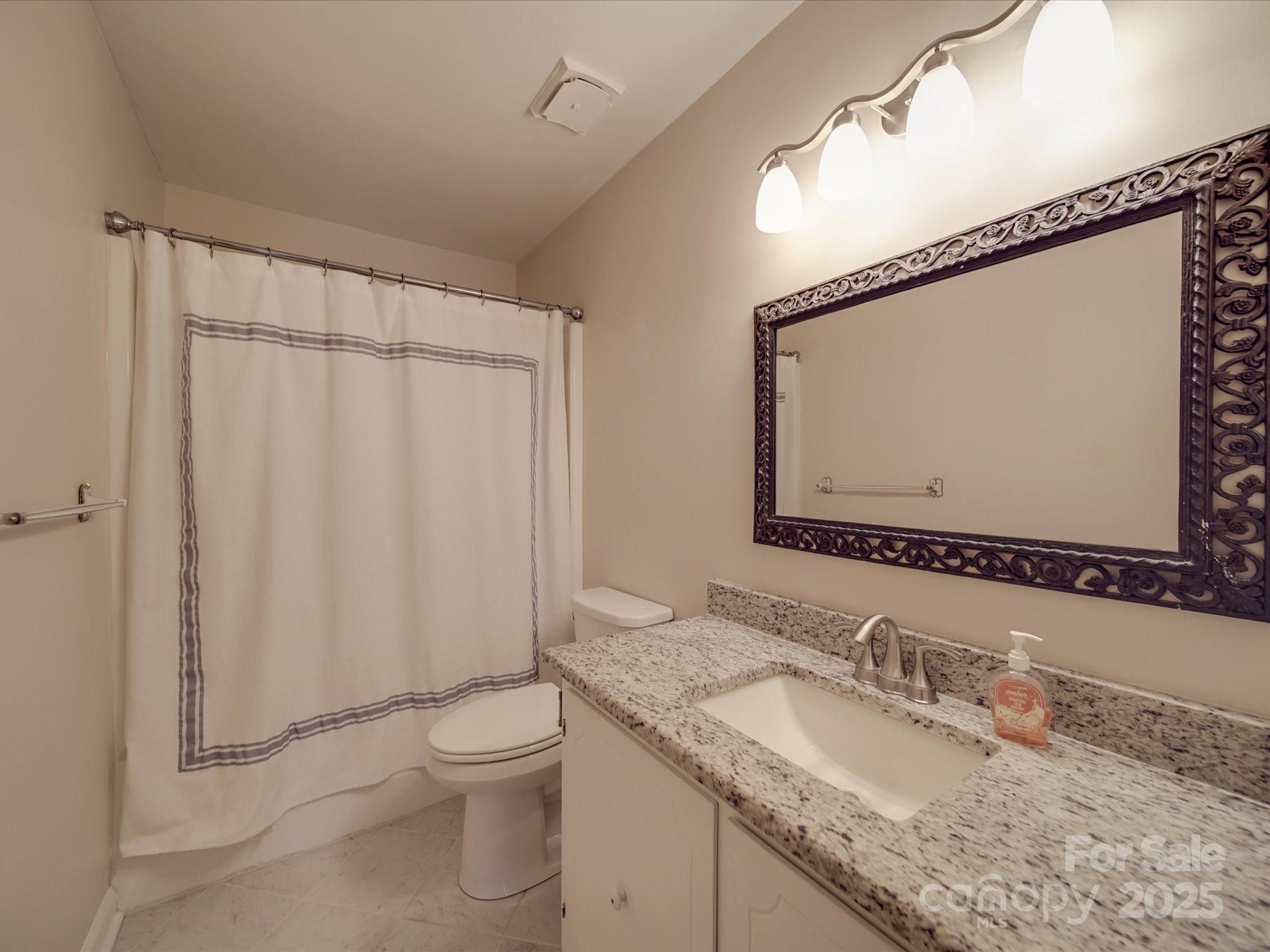 1515 Hasty Road Marshville, NC 28103 - Photo 33 of 40 a bathroom with a granite countertop sink a toilet and a mirror