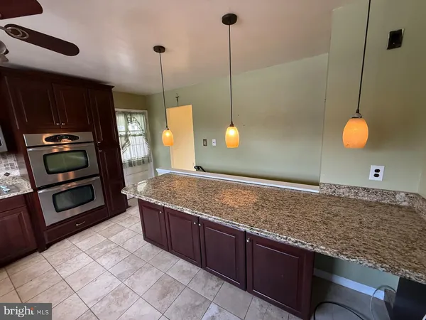 a kitchen with stainless steel appliances granite countertop a sink a stove and a wooden cabinets
