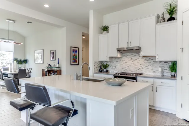 a kitchen with stainless steel appliances granite countertop a stove a sink a refrigerator and white cabinets