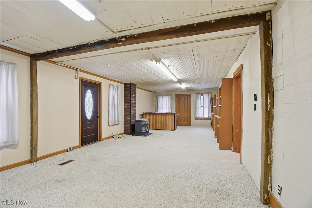 8045 Veto Road Belpre, OH 45714 - Photo 33 of 50 Below grade area with a wood stove, light colored carpet, and wood ceiling