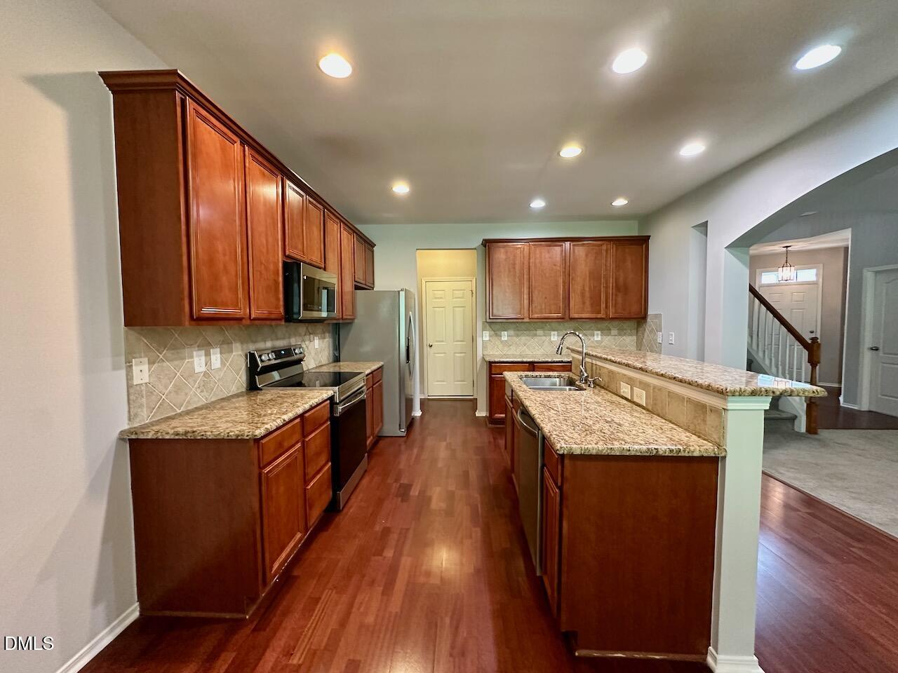 8208 Stone Cellar Drive Raleigh, NC 27613 - Photo 12 of 34 a kitchen with stainless steel appliances granite countertop wooden cabinets a stove top oven a sink and dishwasher