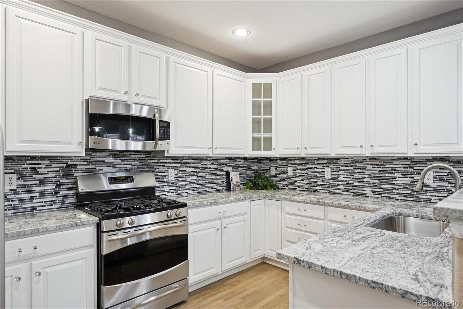 3350 Cascina Circle, Unit D Highlands Ranch, CO 80126 - Photo 12 of 40 a kitchen with granite countertop white cabinets and stainless steel appliances