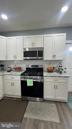 a kitchen with granite countertop a stove a sink and a microwave