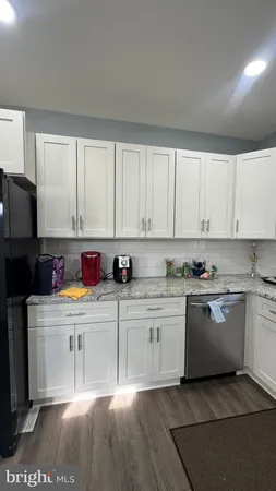 a kitchen with stainless steel appliances granite countertop a stove top oven a sink a refrigerator and white cabinets