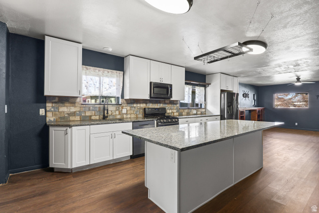 2576 Gramercy Avenue Ogden, UT 84401 - Photo 6 of 20 Kitchen featuring a center island, dark stone countertops, white cabinetry, stainless steel appliances, and dark wood-style flooring