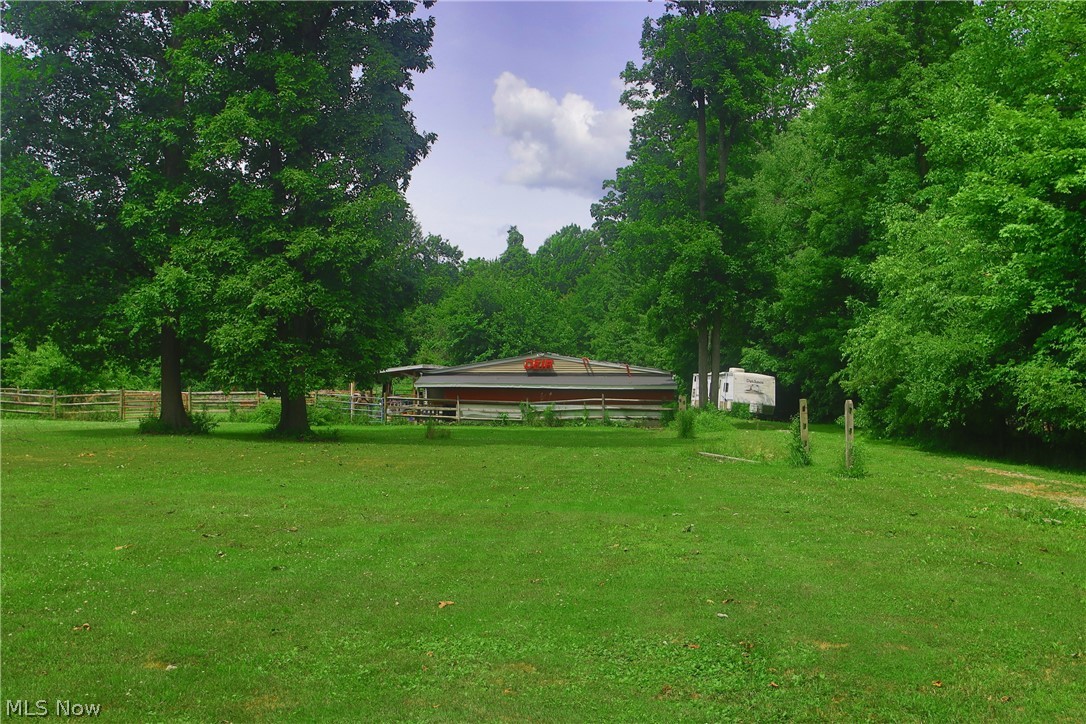 7250 Brakeman Road Painesville, OH 44077 - Photo 5 of 17 Expansive green space featuring a red-sided barn with an attached shed and surrounding wooden fencing