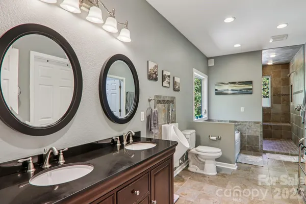 a bathroom with a granite countertop double vanity sink a toilet and a mirror