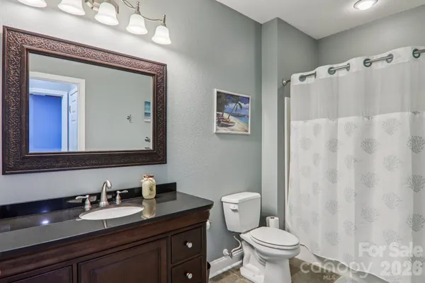 a bathroom with a granite countertop toilet sink and mirror