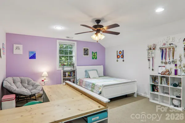 a bedroom with a bed a study table and large window
