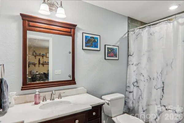 a bathroom with a granite countertop sink toilet a mirror and shower