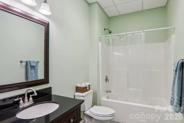 a bathroom with a granite countertop sink toilet a mirror a vanity and shower