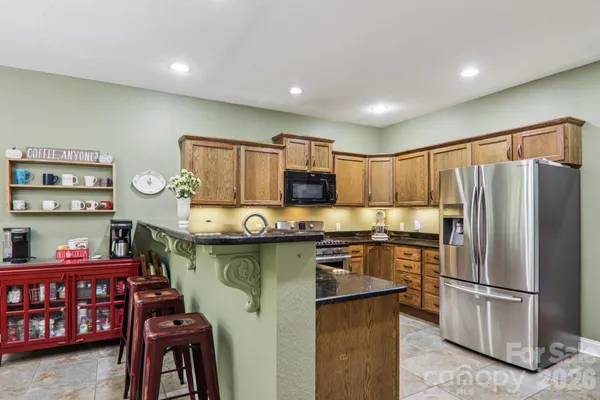 a kitchen with stainless steel appliances granite countertop a refrigerator a stove a sink and a microwave