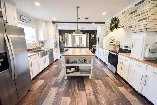 a kitchen with kitchen island granite countertop lots of counter top space a sink appliances and cabinets