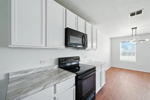 a kitchen with stainless steel appliances granite countertop white cabinets and a stove top oven