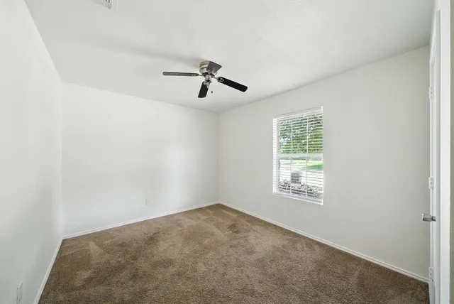 an empty room with windows and fan
