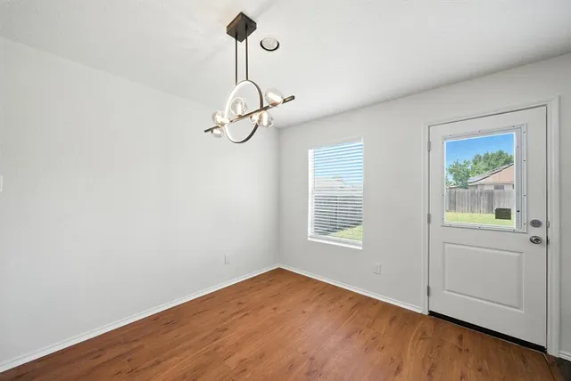 a view of empty room with wooden floor and windows