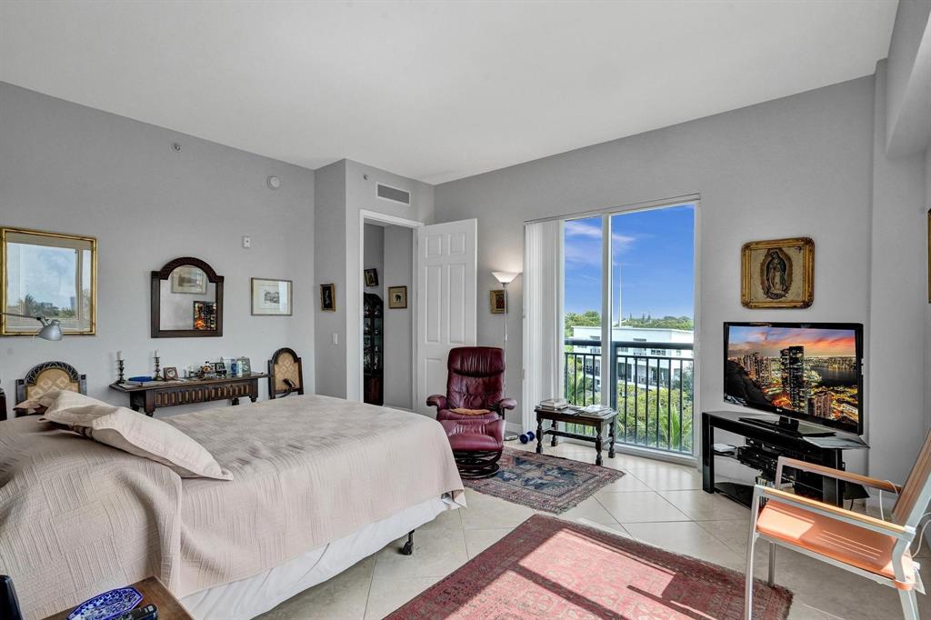 2633 Northeast 14th Avenue, Unit 400 Wilton Manors, FL 33334 - Photo 26 of 74 a living room with furniture a flat screen tv and a floor to ceiling window