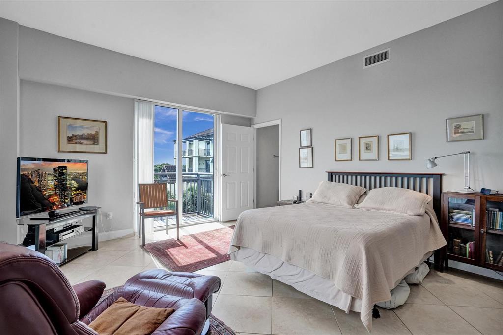 2633 Northeast 14th Avenue, Unit 400 Wilton Manors, FL 33334 - Photo 29 of 74 a spacious bedroom with a bed and glass wall