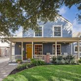 a view of a house with brick walls and a yard with a large tree