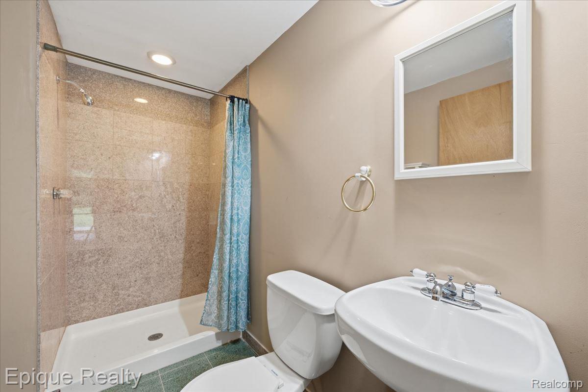 1221 Rhodes Road Lake Orion, MI 48360 - Photo 47 of 72 Full bathroom featuring a walk-in shower with tile surround, a pedestal sink with a chrome faucet, a white toilet, and green tile flooring