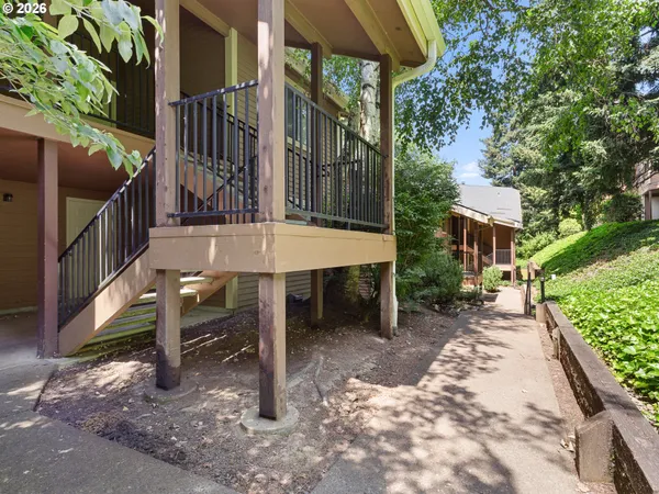 a view of a patio with table and chairs under an umbrella with large trees